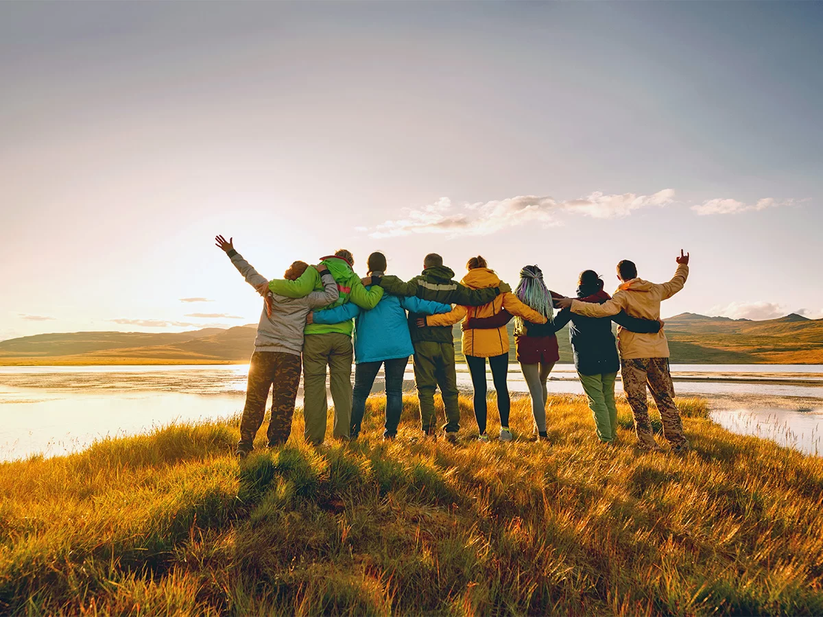 People standing together on a grassy inlet of a lake