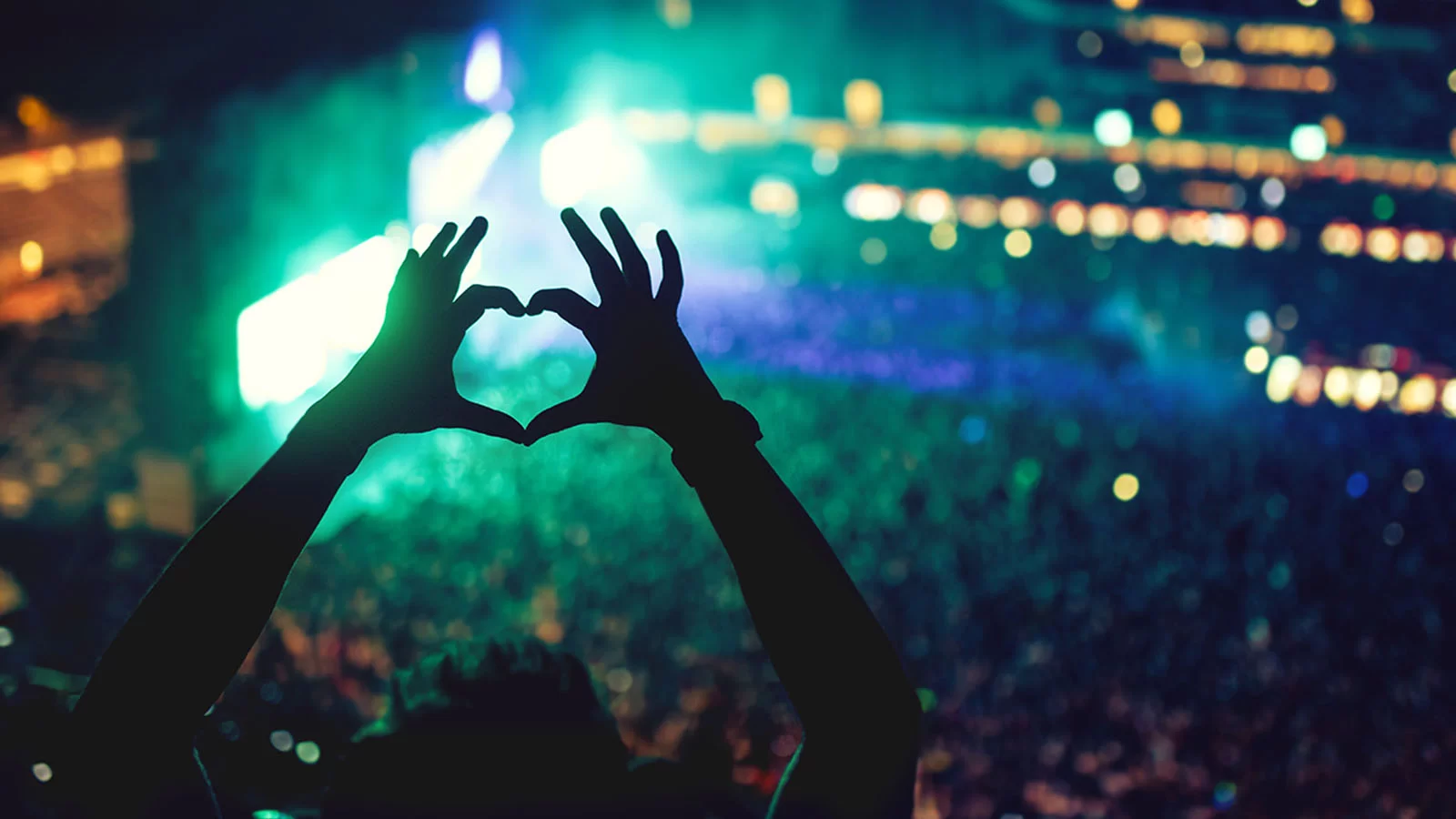 Fingers held up in the shape of a heart at a concert