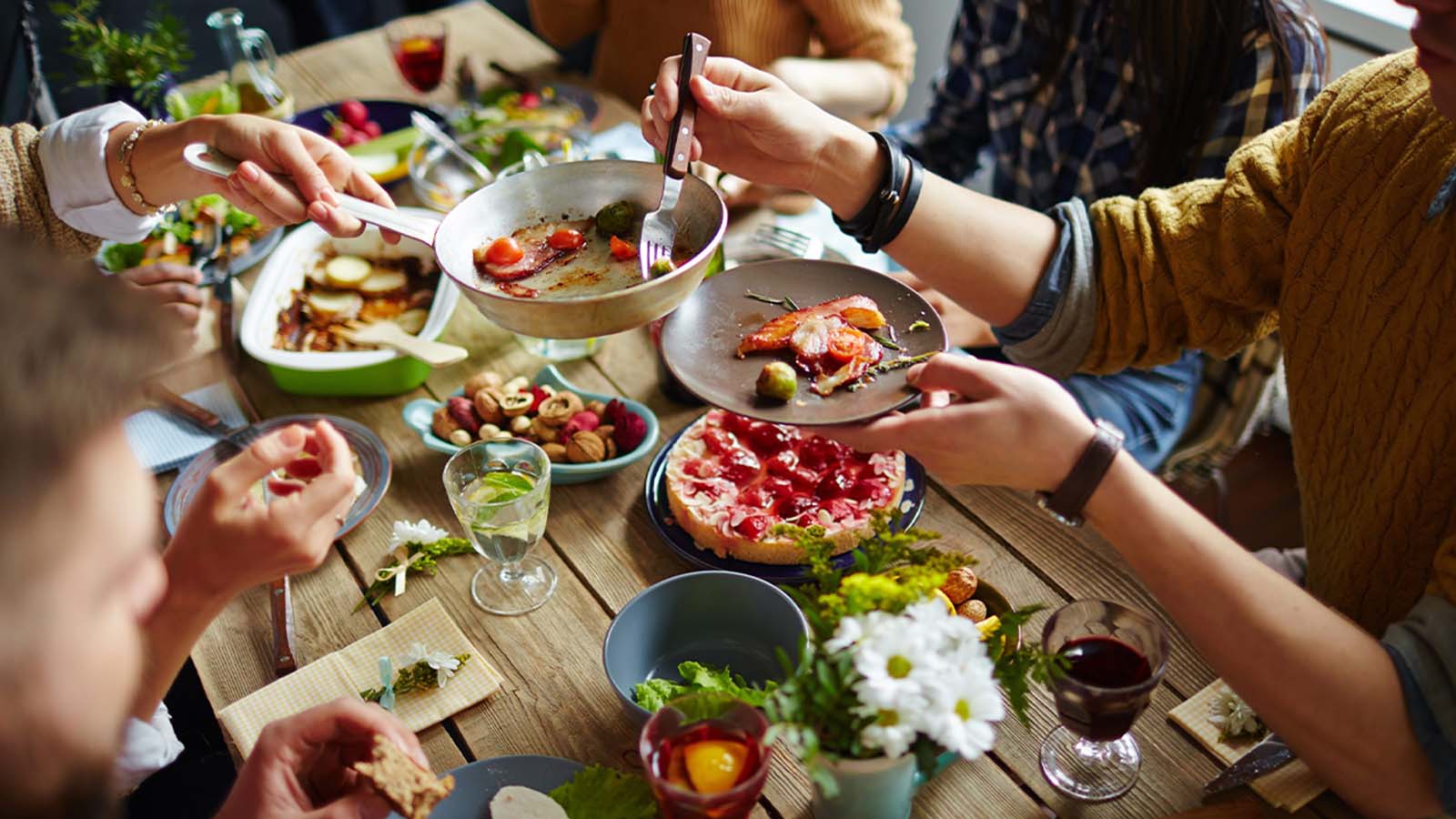 Table full of food with hands sharing dishes family-style