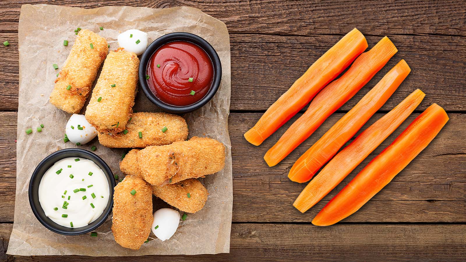 Chicken tenders on paper with ketchup in a ramekin next to carrot sticks