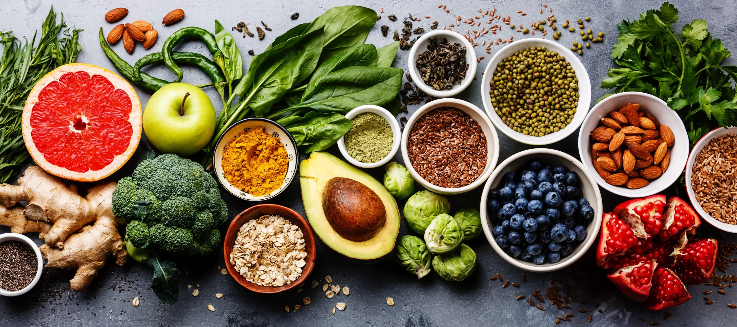 Overhead view of various healthy foods, like grapefruit, avocado, blueberries, nuts and more