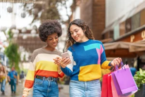 Two female friends walking side by side looking at a cell phone