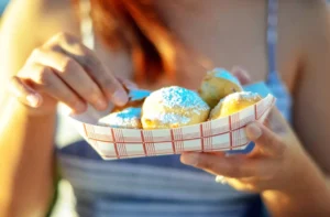 Fried food dusted with powdered sugar in a paper boat