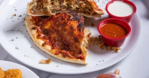 calzone on plate with dipping sauces