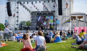 People sitting on a lawn facing the stage at a concert