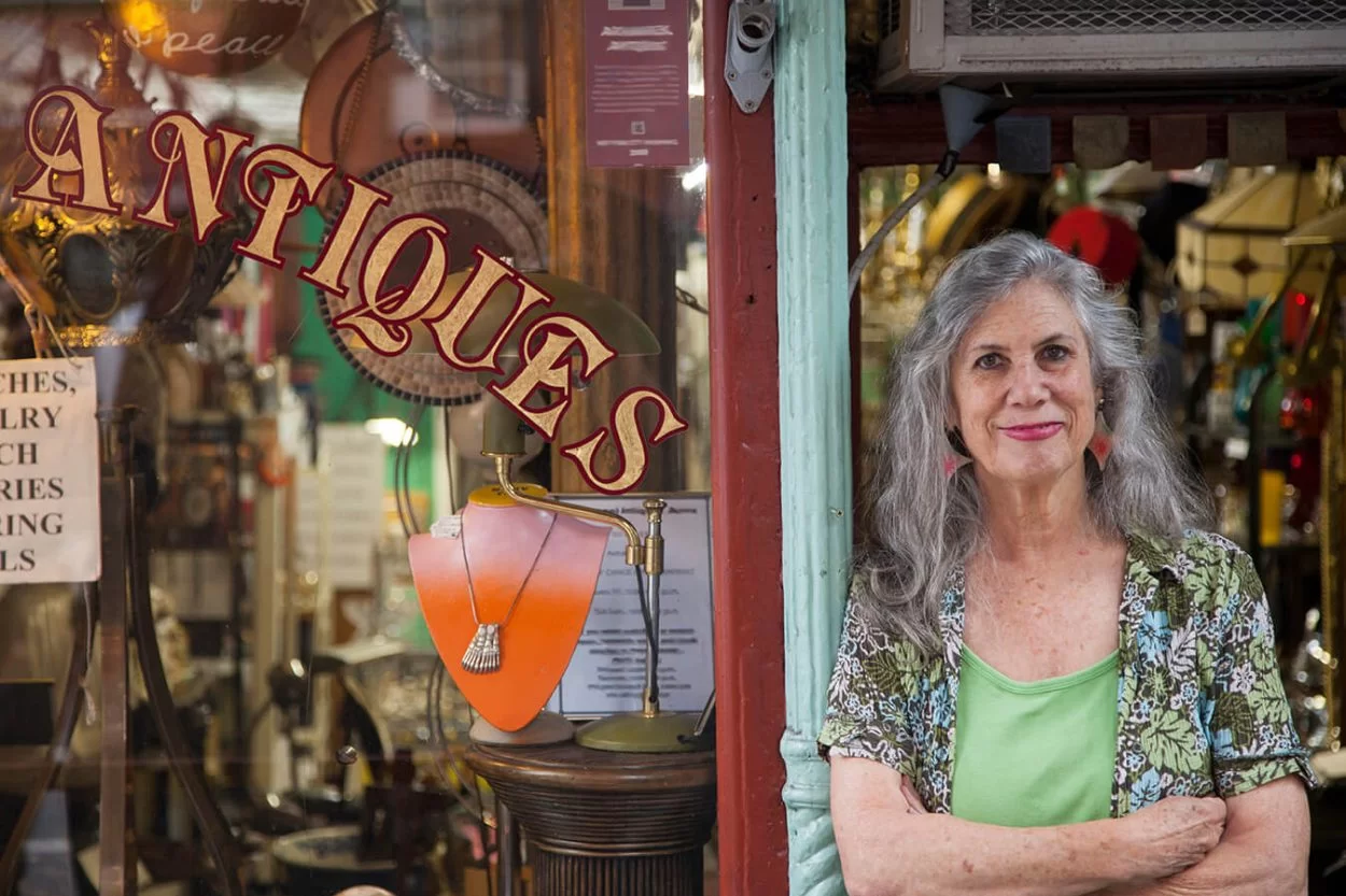 Woman standing outside an antique shop with arms crossed