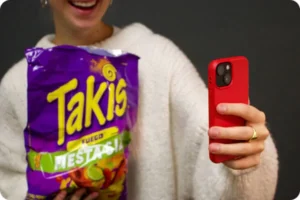 person taking selfie with bag of Takis