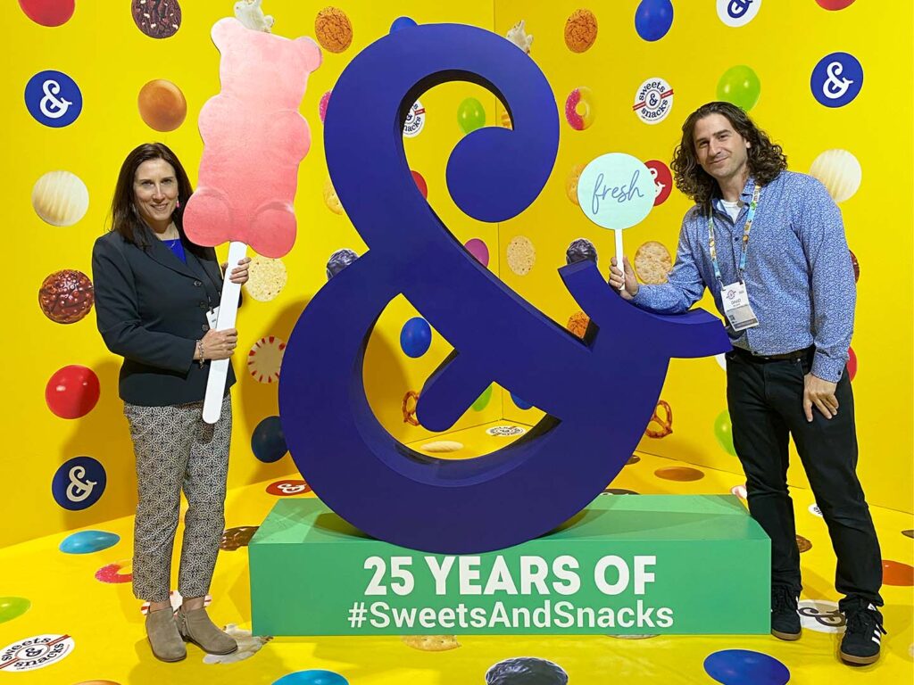 Ampersand selfie station with people posing with giant candy props
