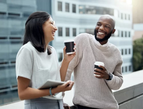 A woman and man drinking coffee outdoors on a balcony