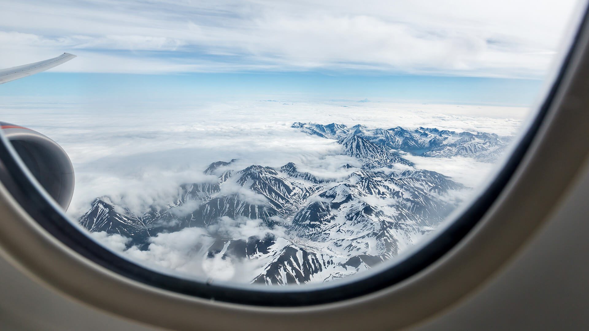 view of a snowy mountain from a window of an airplane