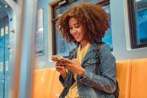 women on subway smiling looking at phone