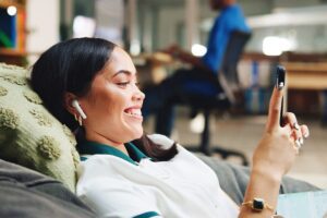 woman laying down smiling while looking at phone